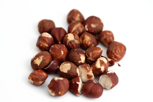 Pile of brown hazelnuts on white background.