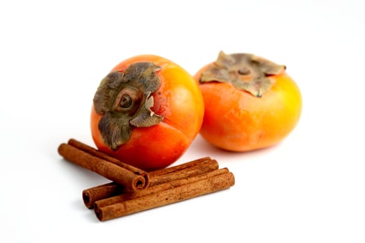 Closeup of persimmons and cinnamon on white background.