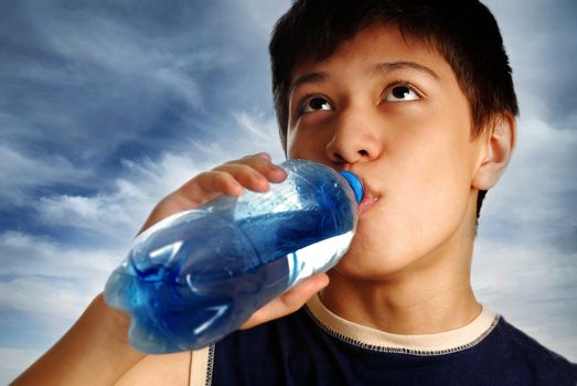 Drinking boy and bottle with mineral water after sport game