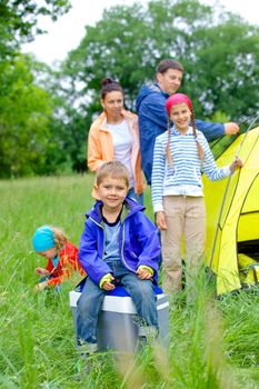 Young boy with his family near tent in camping on the nature
