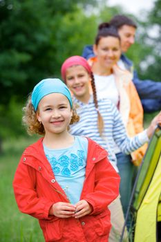 Young girl with her family near tent in camping on the nature