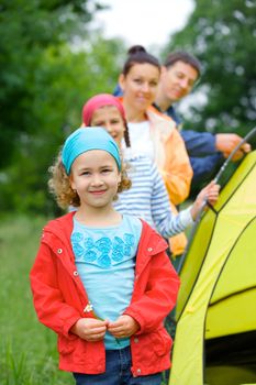 Young girl with her family near tent in camping on the nature