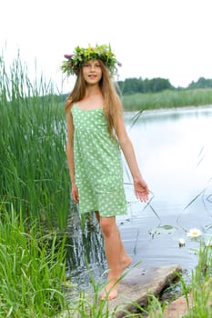 Spring beautiful girl with wreath of flowers near forest lake