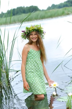 Spring beautiful girl with wreath of flowers near forest lake