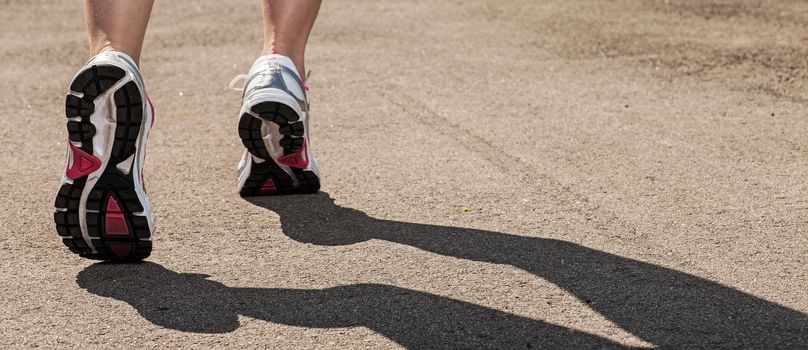 Woman legs in sneakers on asphalt background