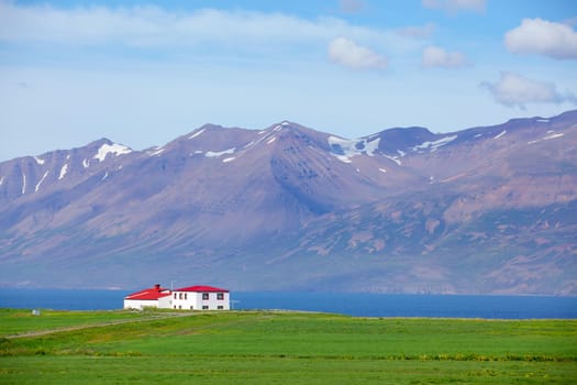 Beautiful house in Iceland. Mountains in background.