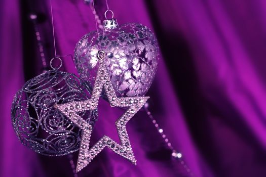 Silver christmas decoration on purple fabric background
