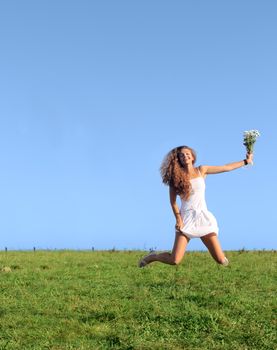 Beautiful girl in white dress jumping on green field