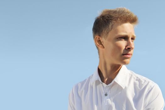 Handsome blond man on blue sky background at sunny day