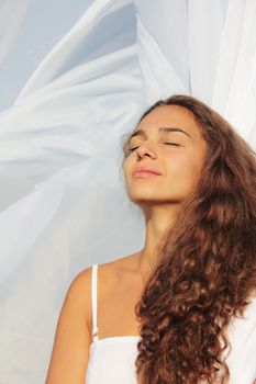 Beautiful young woman with closed eyes on white fabric background
