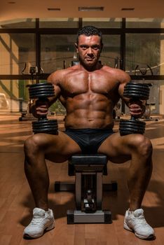 male bodybuilder resting after doing heavy weight exercise