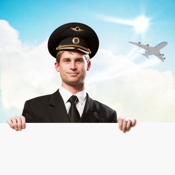 pilot in the form of holding an empty billboard on the background of sky and flying plane, place for text