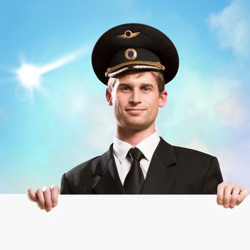 pilot in the form of holding an empty billboard on the background of sky with clouds, place for text