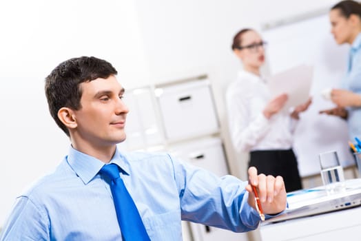 Portrait of a businessman in a blue shirt in the background of colleagues discussing