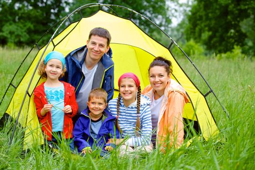 Family with three kids in tent in camping on the nature.