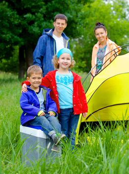 Summer, family camping - lovely sister and brother with parents near camp tent. Vertical view