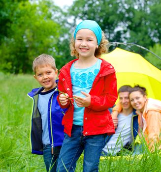 Summer, family camping - lovely sister and brother with parents near camp tent