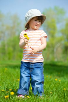 Sweet beautiful girl sitting on a green meadow with dandelions