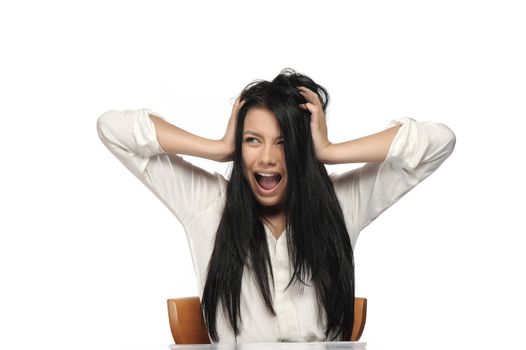 A frustrated and angry woman is screaming out loud and pulling her hair. 
