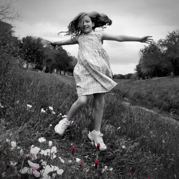 happy children girl jumping on spring poppy flowers meadow with motion blur