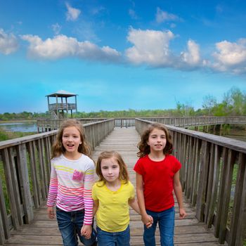 sister friends walking holding hands on lake wood smiling