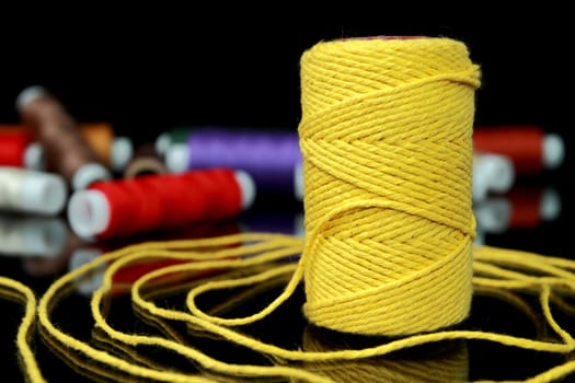 Focus on one reel of thread on a black background
