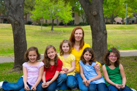 Mother teacher with daughter pupils in playground park group portrait on lawn