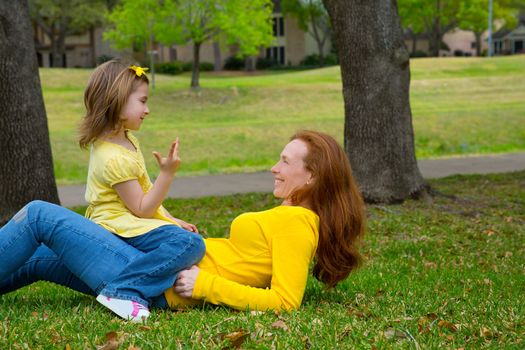 Daughter and mother playing counting lying on park lawn