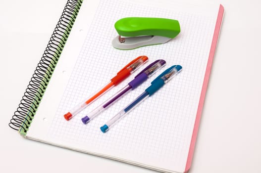 book with pens and stapler on a white background