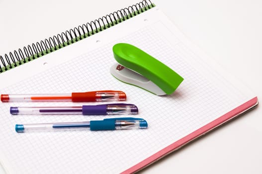 book with pens and stapler on a white background