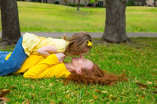 Daughter and mother nose kissing lying on park lawn outdoor