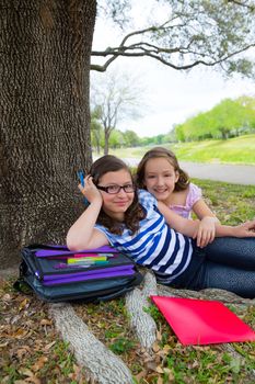 sister firends girls relaxed under tree park after school with bag and folders