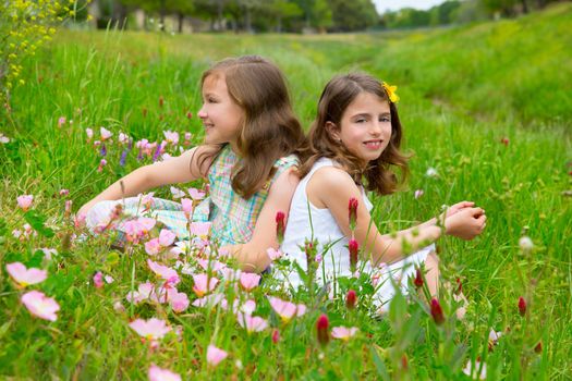 children friends girls on spring meadow with poppy flowers