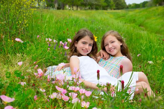 children friends girls on spring meadow with poppy flowers