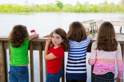 Children girls rear view looking at lake on railing and one looking behind