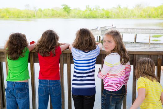 Children girls rear view looking at lake on railing and one looking behind