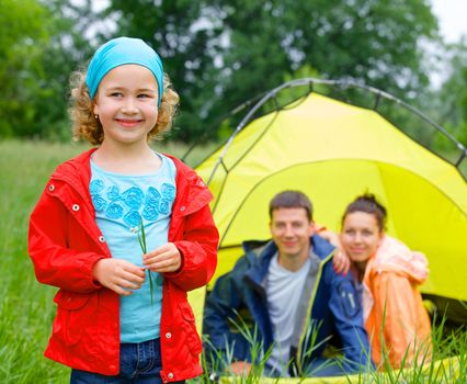 Young girl with his family near tent in camping on the nature