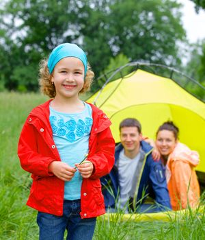 Young girl with his family near tent in camping on the nature