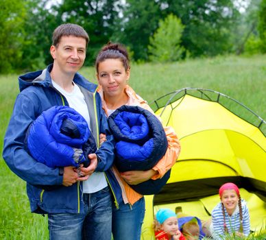 Young happy couple camping near tent in park