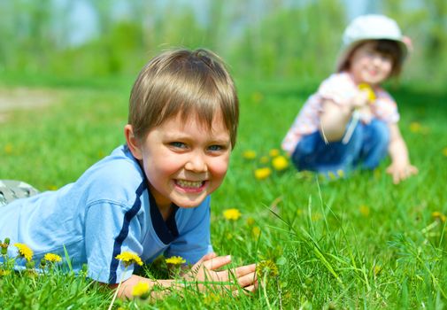 Sweet beautiful girl sitting on a green meadow with dandelions