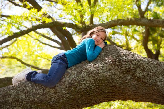 Beautiful children kid girl resting lying on a tree branch