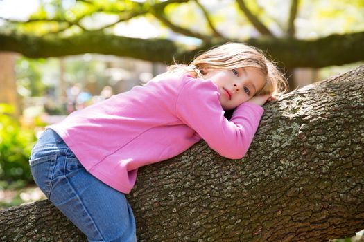 Beautiful children kid girl resting lying on a tree branch