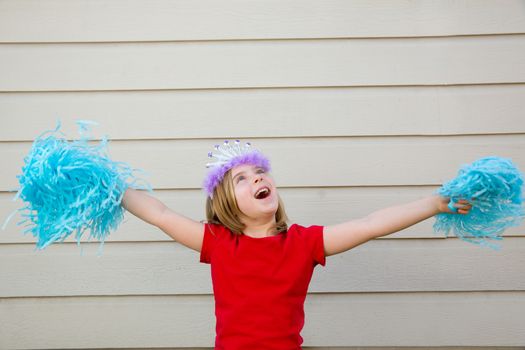 Blond kid girl playing like cheerleading pom poms with princess crown