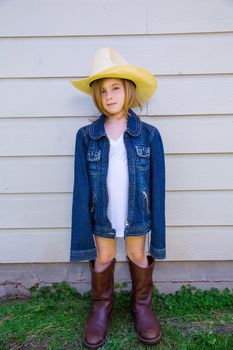 Little kid girl pretending to be a cowboy with father boots and hat