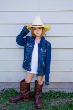 Little kid girl pretending to be a cowboy with father boots and hat
