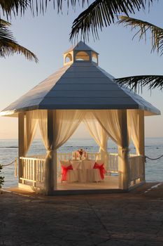 A tropical beach gazebo at sunrise, set and ready for a romantic breakfast for two at a resort in the Mayan Riviera, Mexico