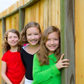 Grils group in a row smiling in a wooden fence outdoor