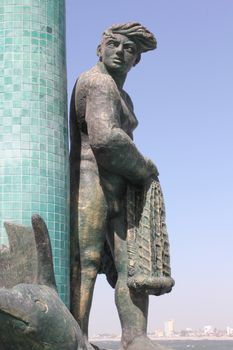 A fountain featuring a bronze fisherman with Old Mazatlan in the background