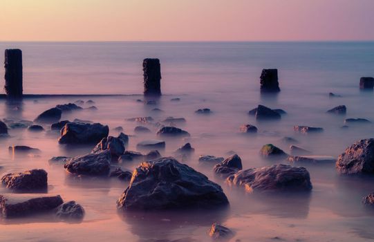 Sunset light falls across the rocks at low tide on the beach at Leysdown in Kent