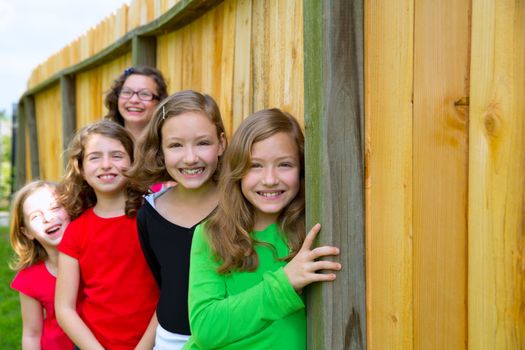 Grils group in a row smiling in a wooden fence outdoor